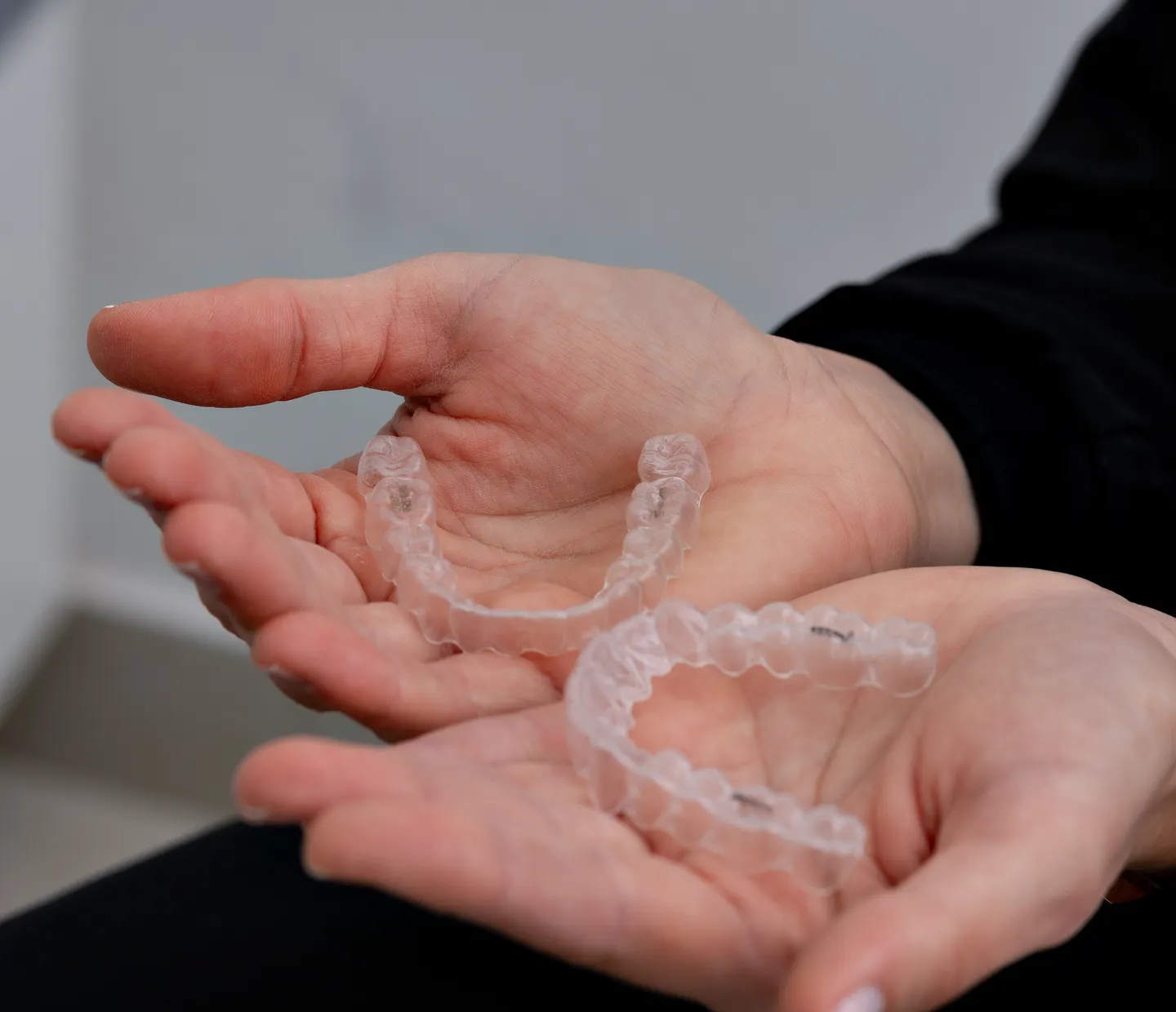 A clear aligner held up in daylight